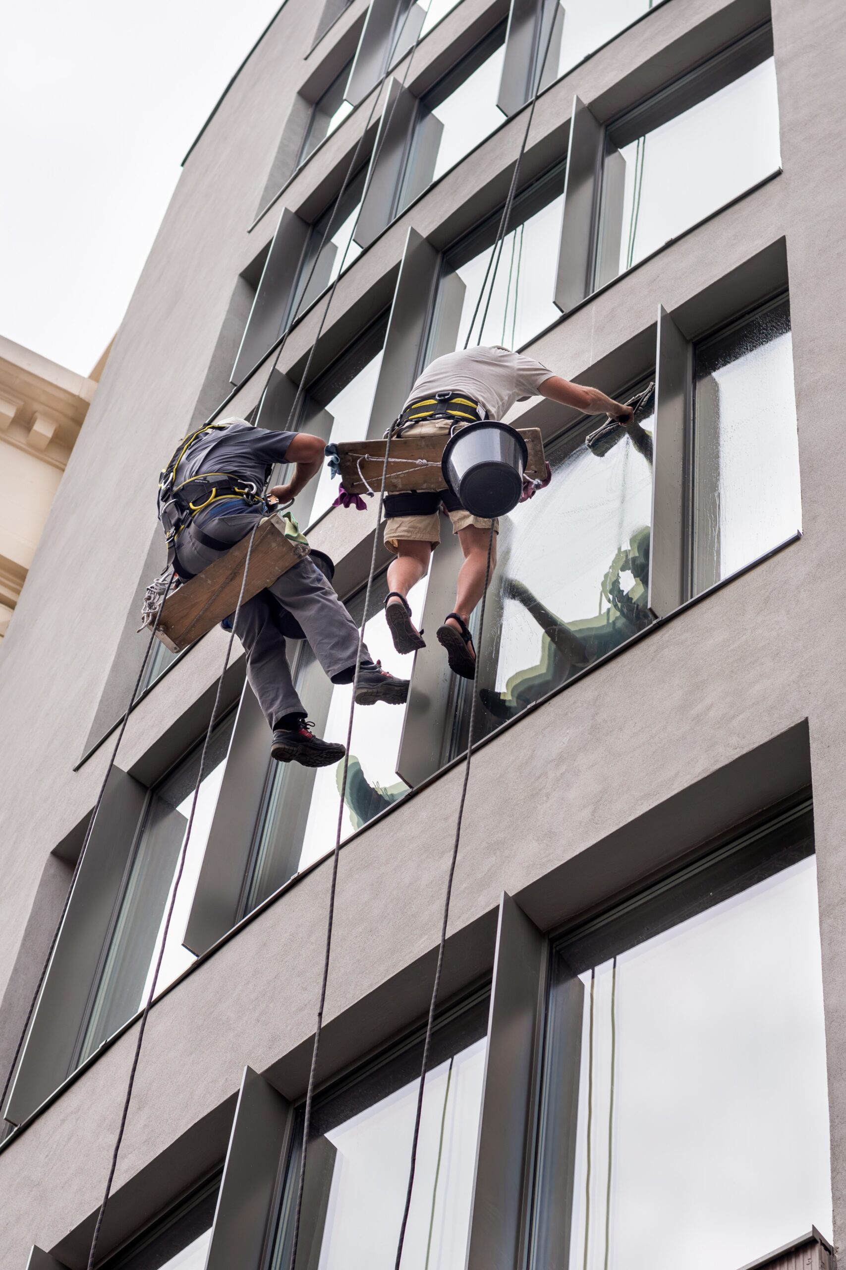 Two workers washing windows outside a modern building